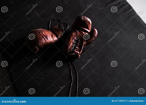 Luvas De Boxe De Couro Castanho Numa Tela De Treino Para Fundo Preto