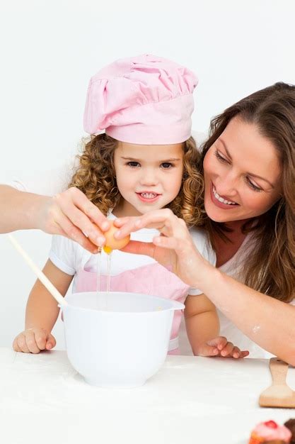 Mãe mostrando a sua filha como quebrar ovos Foto Premium