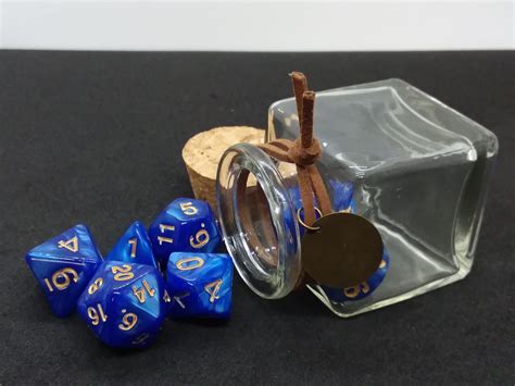 A Glass Jar Filled With Blue Dice Next To Two Corks And A Wooden Slice