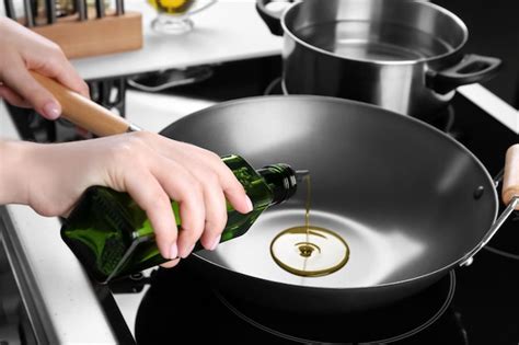 Mujer Verter Aceite De Botella En Wok En Cocina Foto Premium