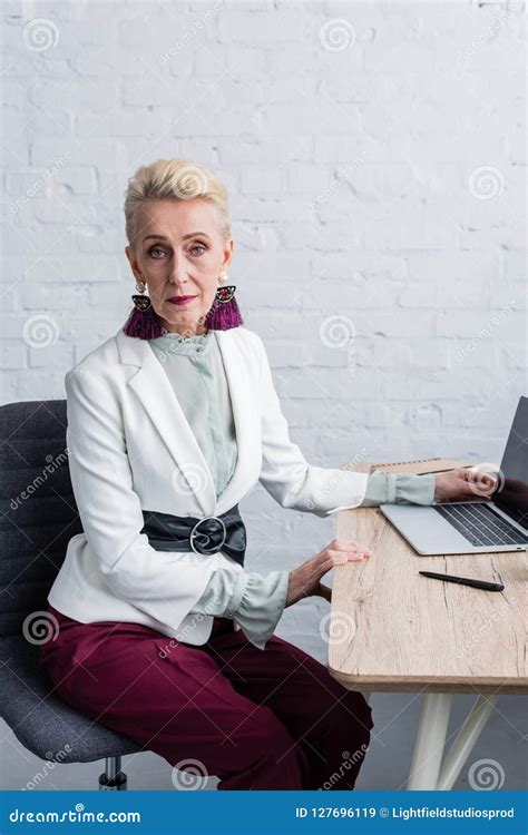 Elegant Senior Businesswoman In White Suit With Laptop Stock Image