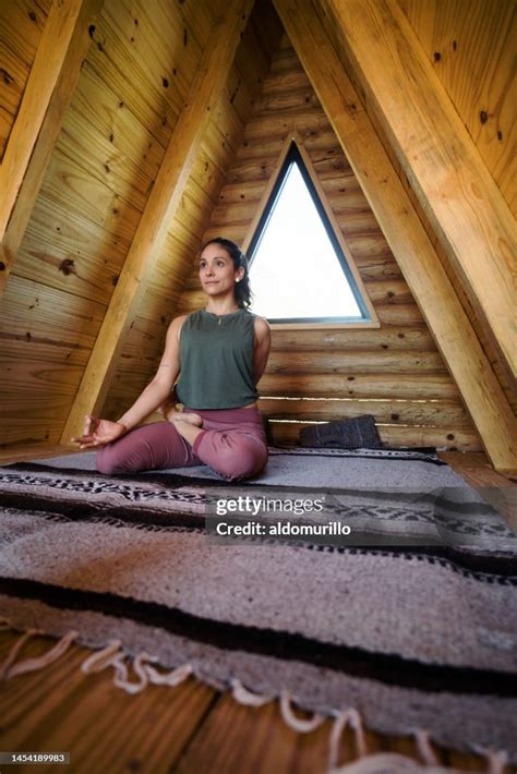 Young Woman Holding Yoga Posture In Log Cabin Room High Res Stock Photo