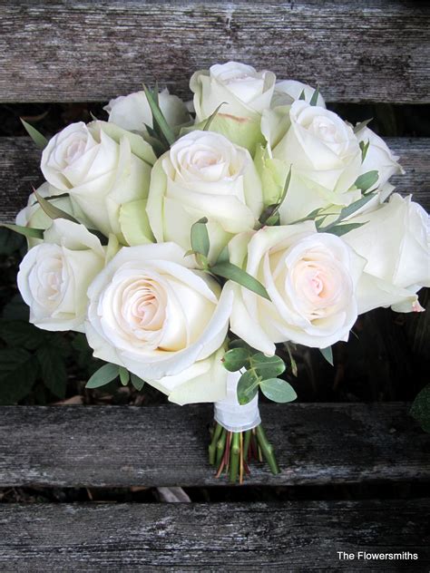 A Bouquet Of White Roses Sitting On Top Of A Wooden Bench