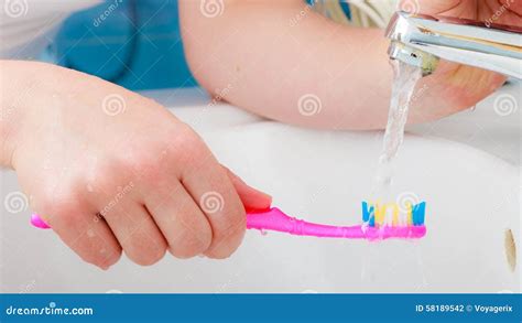 Toothpaste On Toothbrush In Hand In The Bathroom Sink Stock Photo