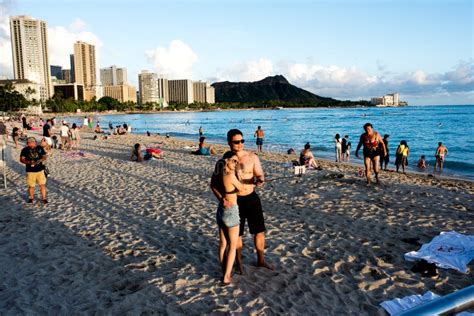 Tourist Sunbathing And Surfing On The Waikiki Beach In Hawaii