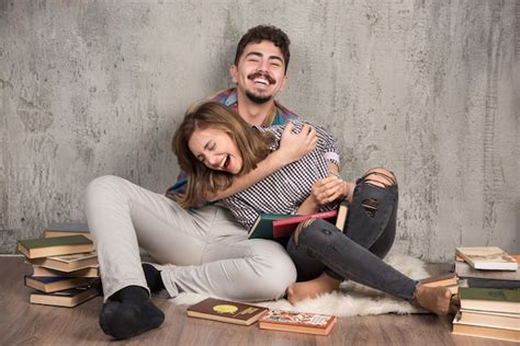 Joli Couple Assis Sur Le Sol Avec Beaucoup De Livres Photo Gratuite