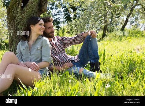 Young Couple Sitting Leaning Against Tree Together Stock Photo Alamy