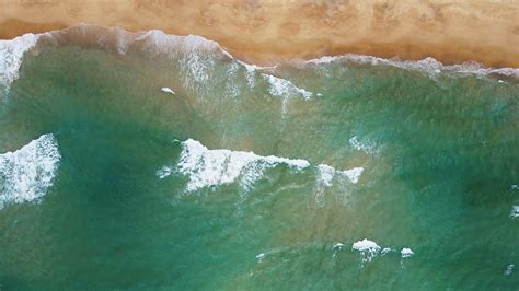 Aerial View Of White Sand Beach And Water Surface Texture Foamy Waves With Sky Beautiful