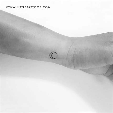 a black and white photo of a person's arm with a small crescent tattoo ...