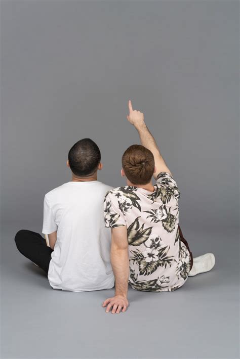 Photo de Vue arrière de deux jeunes hommes assis l un près de l autre