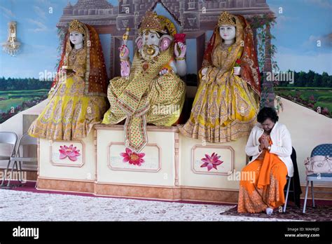 A Hindu Worshiper Praying And Meditating Near Statues Of Gods And