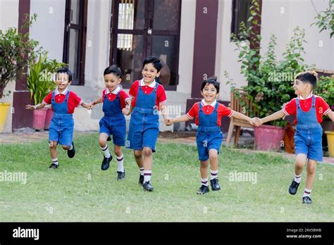 Happy indian school kids holding hands playing and running outside the ...