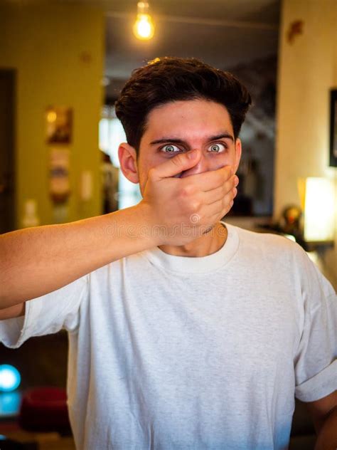 Handsome Young Man Covering His Mouth With Hand At Home Stock Image