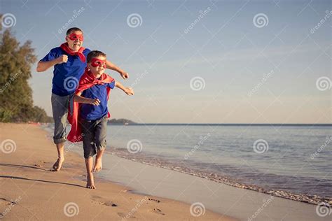 Fader Och Son Som Spelar Superheroen P Stranden P Dagtiden Arkivfoto