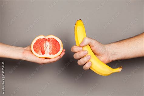 Erotic Banana And Donut In The Hands As A Symbol Of The Penis And Vagina Isolated On A Grey