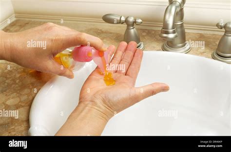 Foto horizontal de manos femeninas poner jabón líquido en la palma de