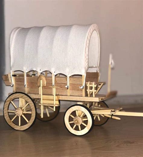 A Wooden Wagon With White Cloth On The Back And Wheels Is Sitting On A