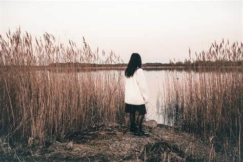 Premium Photo Rear View Of Girl Standing By Plants At Lakeshore Against Clear Sky