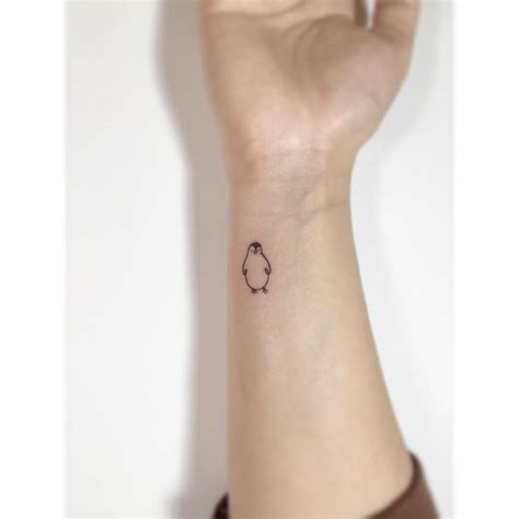 Minimalistic tattoo of a penguin located on the wrist.