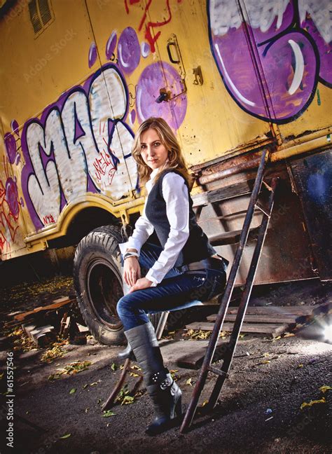 Sexy Blonde Woman Sitting On Stairs Against Cabin With Graffiti Stock Photo Adobe Stock