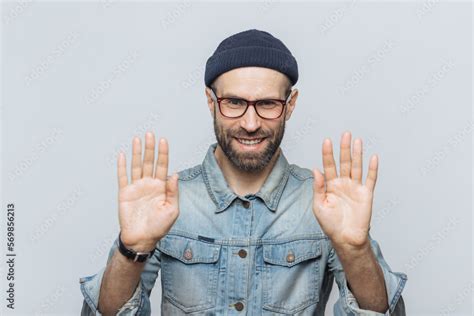 Horizontal Shot Of Handsome Bearded Male Shows Palms At Camera