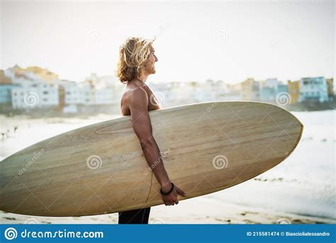 Surfer Male With A Muscular Body With His Surfboard At The Beach