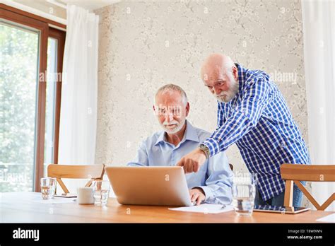 Two Seniors In Teamwork At Laptop Computer In A Computer Class Stock