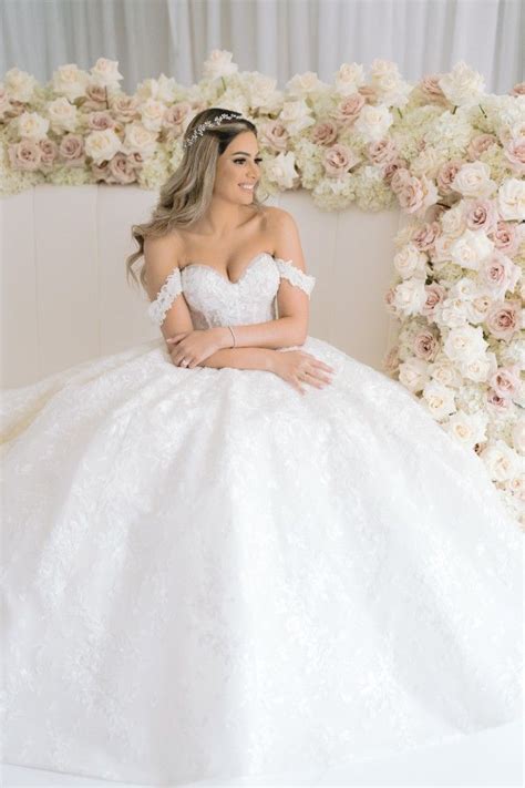 A Woman In A White Wedding Dress Sitting On A Flower Covered Bench With