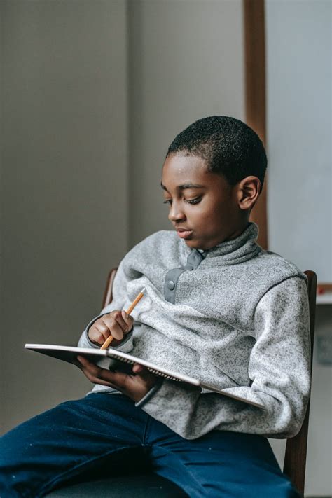 Focused black boy writing in notebook · Free Stock Photo