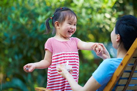 Happy Little Asian Girl Eating Ice Cream With Her Mother In The Yard