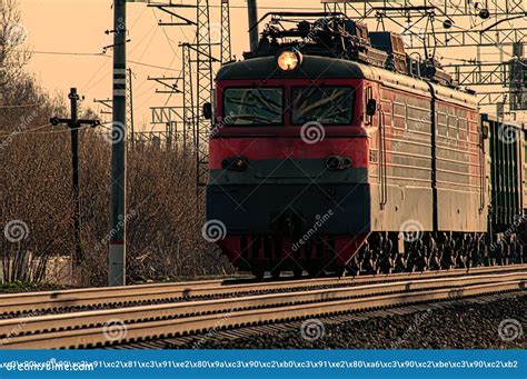 A Powerful Red Diesel Locomotive Pulls A Long Freight Train Along The