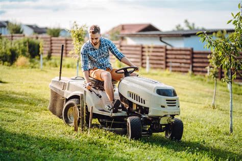 Portrait Of Industrial Gardener Driving A Riding Lawn Mower In In A