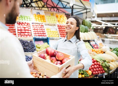 Cheerful Content Attractive Young Female Grocer In Apron Giving Box Of