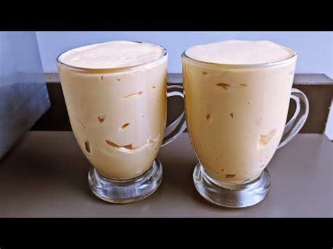 Two Glasses Filled With Liquid Sitting On Top Of A Table