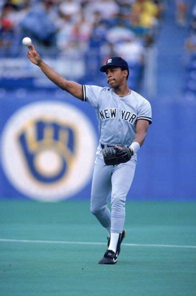 A Baseball Player Throwing A Ball On Top Of A Field In Front Of A Crowd