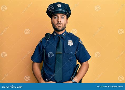 Handsome Hispanic Man Wearing Police Uniform Relaxed With Serious