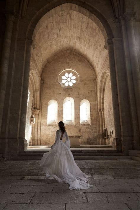 A Woman In A White Wedding Dress Is Standing In An Old Building With