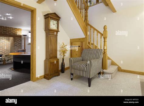 Upholstered Armchair Next To Grandfather Clock In Hallway Stock Photo