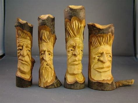 Four Carved Wood Pieces With Faces In The Middle One Is Yellow And The