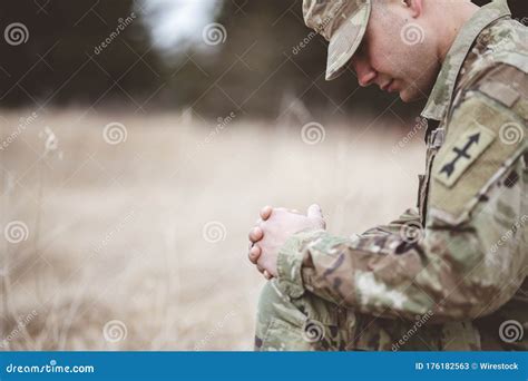 Shallow Focus Shot Of A Young Soldier Praying While Kneeling On A Dry