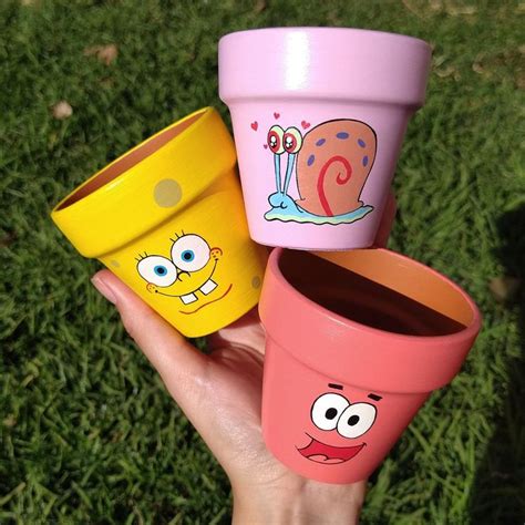 Three Colorful Cups With Faces Painted On Them Are Held Up In The Air