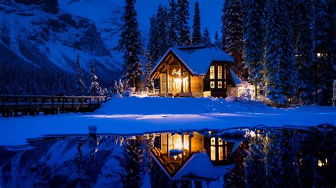 Oświetlony nocą dom w śniegu nad jeziorem Emerald Lake