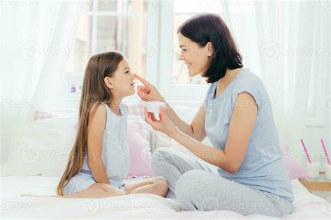 Mother Applying Cream On Daughters Nose Shared Skincare Routine