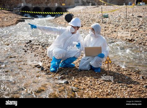 Biologist Wear Protective Suit And Mask Collects Sample Of Waste Water