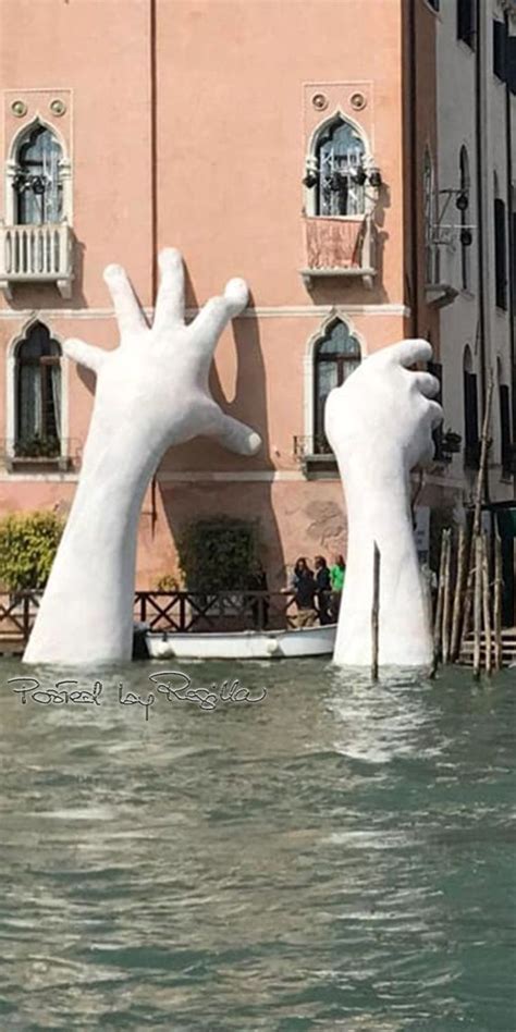 Two Large White Hands Sticking Out Of The Water In Front Of A Building