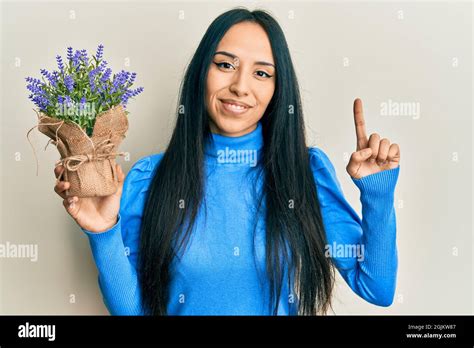 Young Hispanic Girl Holding Lavender Plant Smiling With An Idea Or