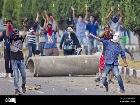 A Kashmiri Muslim Protester Throws Stones At Indian Troops As Others