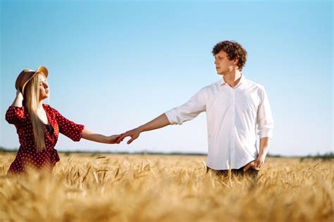 Joven pareja feliz abrazándose en un campo de trigo al atardecer