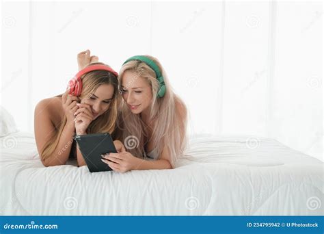 Two Caucasian Girls Wear Bikini On The Bed Playing With Tablet And