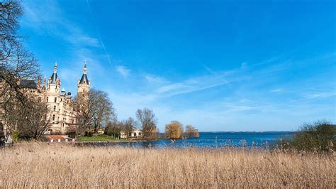 White And Brown Concrete Building Beside Body Of Water Under Blue Sky At Daytime Free Photos